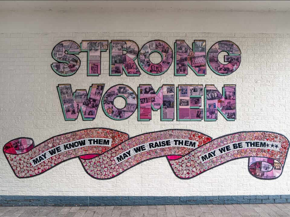 A ceramic mural made up of hundreds or ornately decorated ceramic hearts that says “Strong Women. May we know them. May we be them. May we raise them”